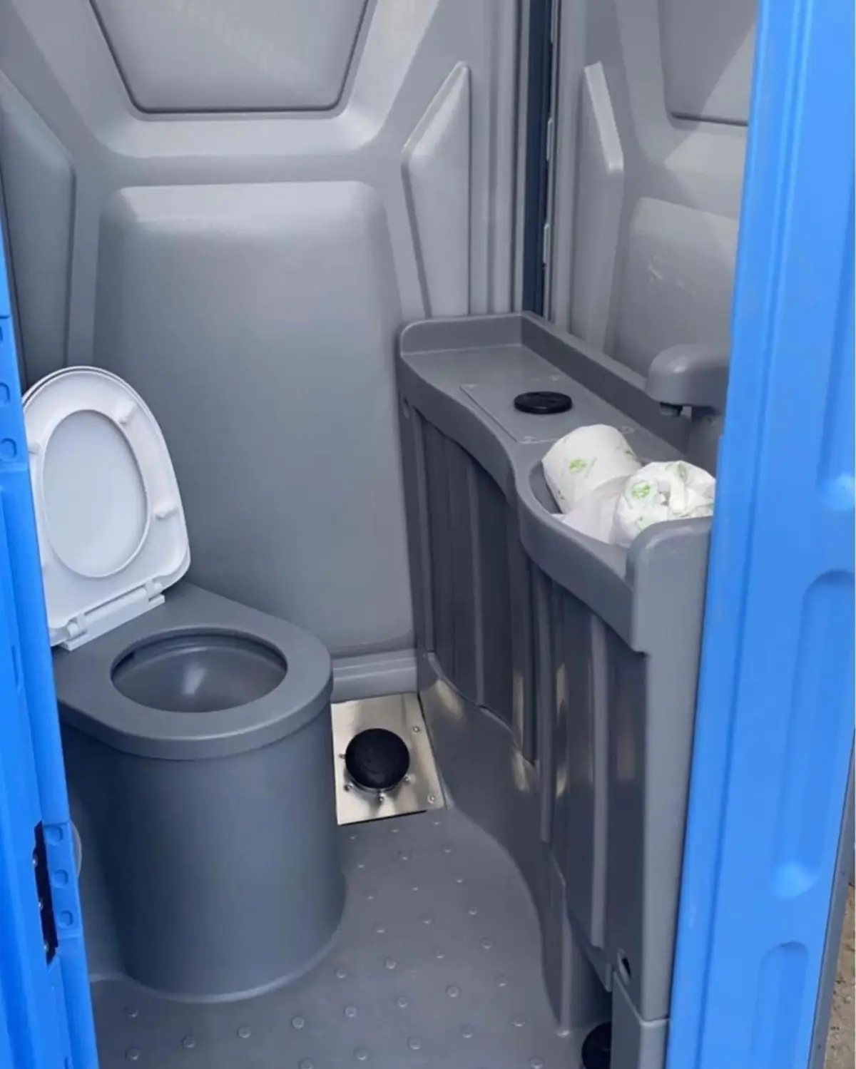 Inside a deluxe portable toilet with a sink beside the seat