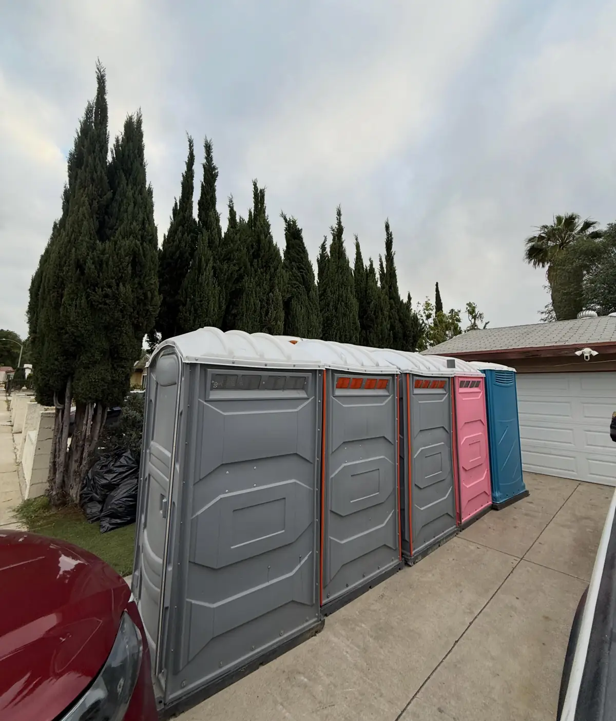Row of portable toilets lined up along a fence