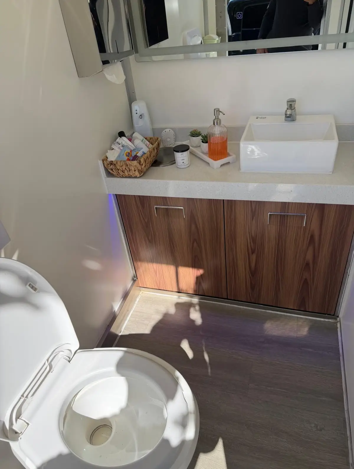 Vanity with vessel sink, mirror and warm lighting inside a restroom trailer