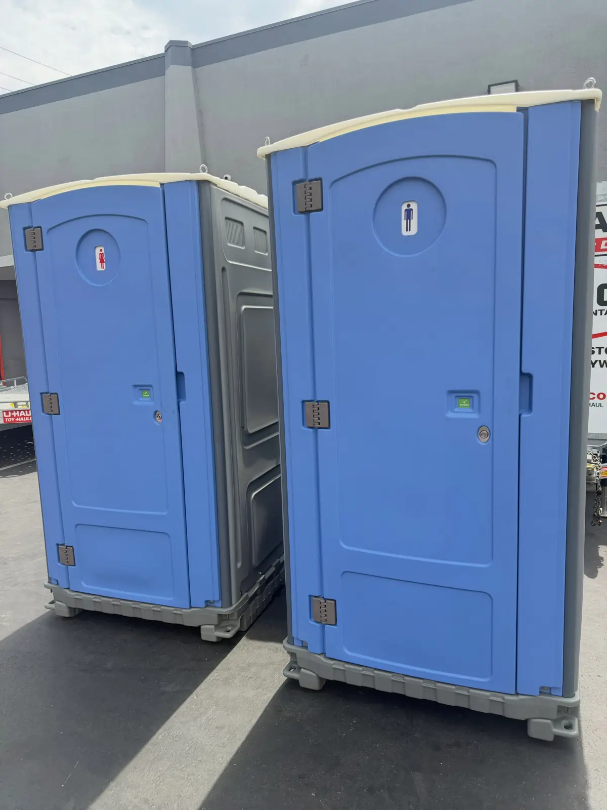 Two porta potties on asphalt