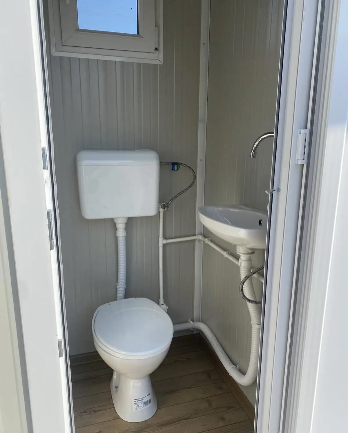Inside a luxury restroom cabin with a white flushing toilet and corner sink